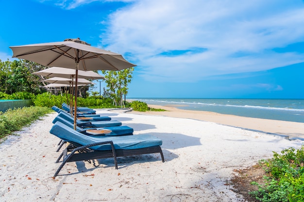 Regenschirm und Stuhl auf dem Strandseeozean mit blauem Himmel und weißer Wolke