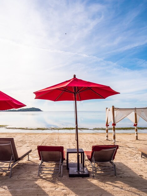 Regenschirm und Stuhl auf dem tropischen Strandmeer und -ozean