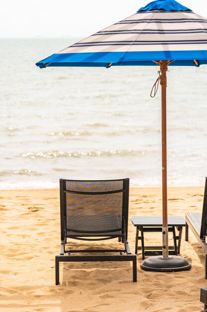 Regenschirm und Stuhl um Strandmeer mit blauem Himmel