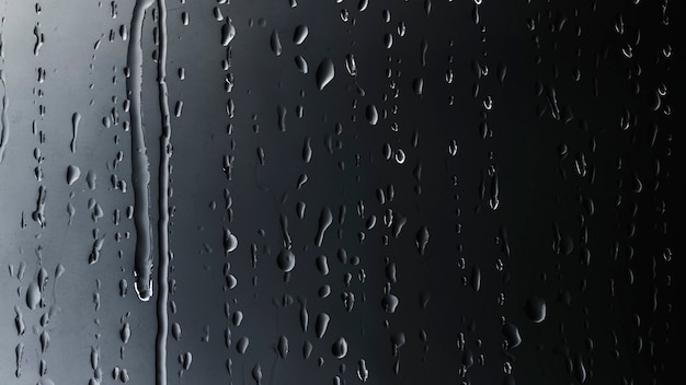 Regentropfen auf schwarzem Glashintergrund