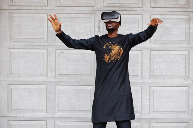 Reicher afrikanischer Mann in stilvoller traditioneller Kleidung in vr-Brille Konzept der Zukunft Afrikas