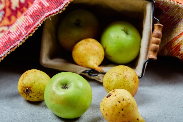Kostenloses Foto reife äpfel und birnen im korb und auf weißer oberfläche.