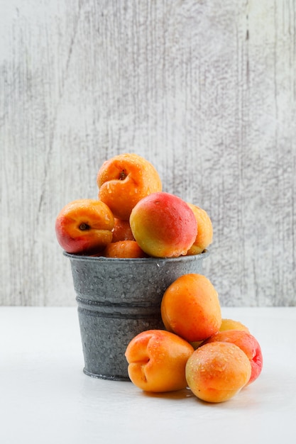 Kostenloses Foto reife aprikosen in einem mini-eimer. seitenansicht.