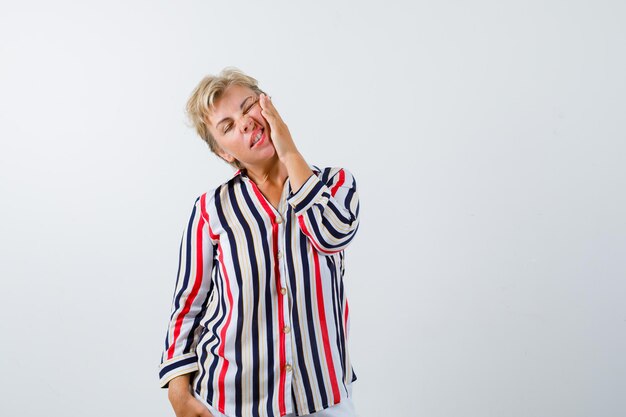 Reife blonde Frau in einem vertikal gestreiften Hemd