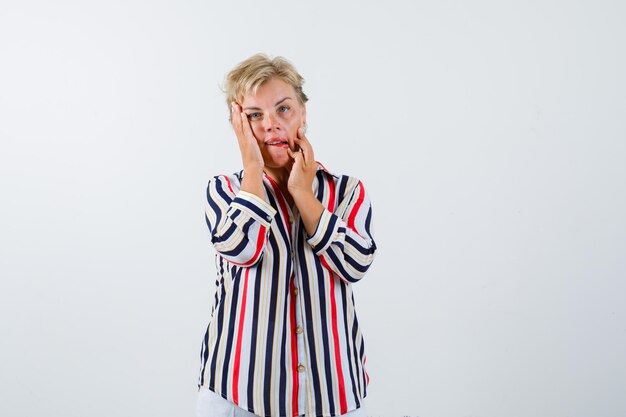 Reife blonde Frau in einem vertikal gestreiften Hemd