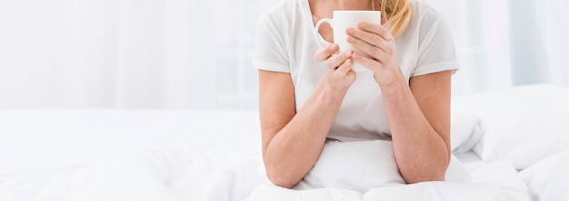 Reife Frau der Nahaufnahme, die einen Tasse Kaffee genießt