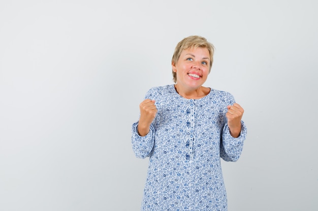 Reife Frau, die Erfolgsgeste im Kleid zeigt und lustig schaut.