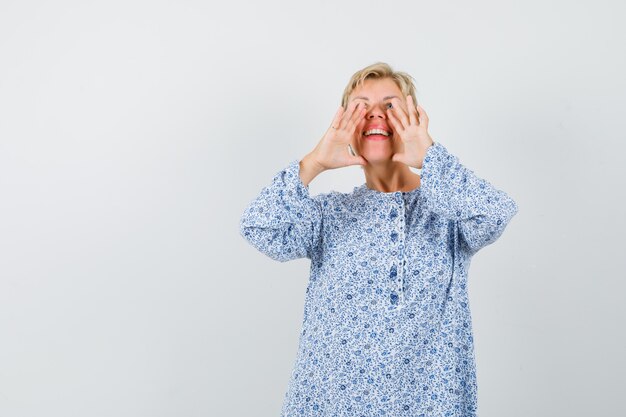 Reife Frau, die etwas im Kleid schreit oder ankündigt und glücklich aussieht.