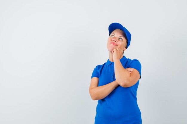 Reife Frau, die im blauen T-Shirt oben schaut und nachdenklich schaut