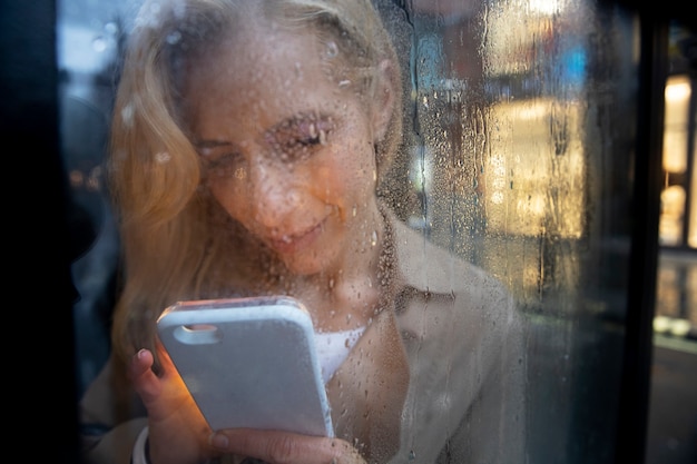 Reife Frau SMS am Telefon, während es regnet