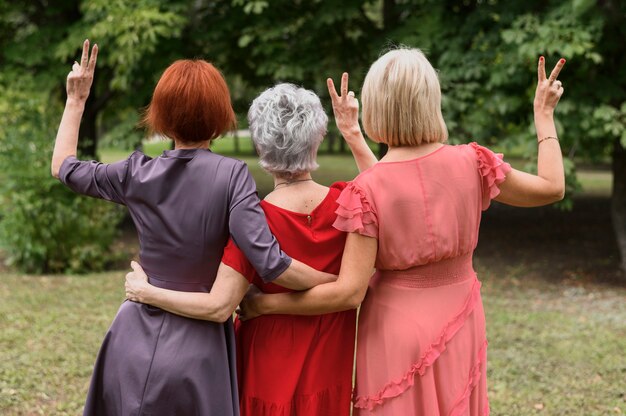 Reife Frauen der hinteren Ansicht, die Friedenszeichen zeigen