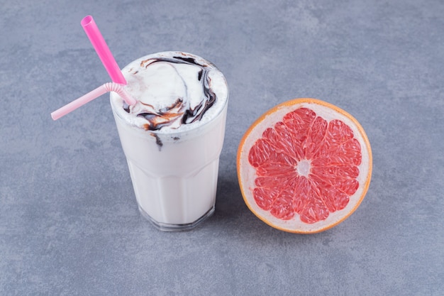 Reife Grapefruit mit frisch gemachtem Milchshake auf grauer Hintergrundnahaufnahme.