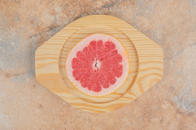 Reife Grapefruitscheibe auf Holzteller.