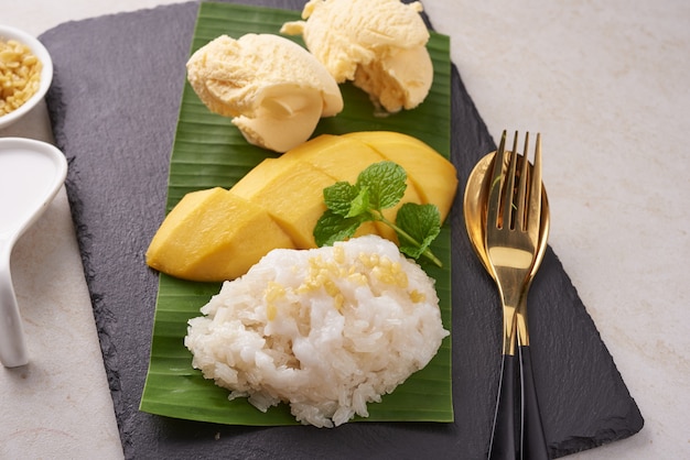 Reife Mango und Klebreis, Eis mit Kokosmilch auf Steinoberfläche, thailändisches süßes Dessert in der Sommersaison. Tropische Frucht. Dessertfrucht. Draufsicht.