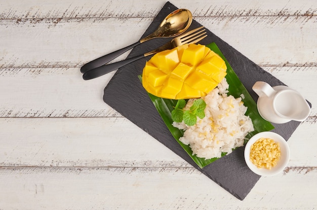 Reife mango und klebreis mit kokosmilch auf steinoberfläche, thailändisches süßes dessert in der sommersaison.