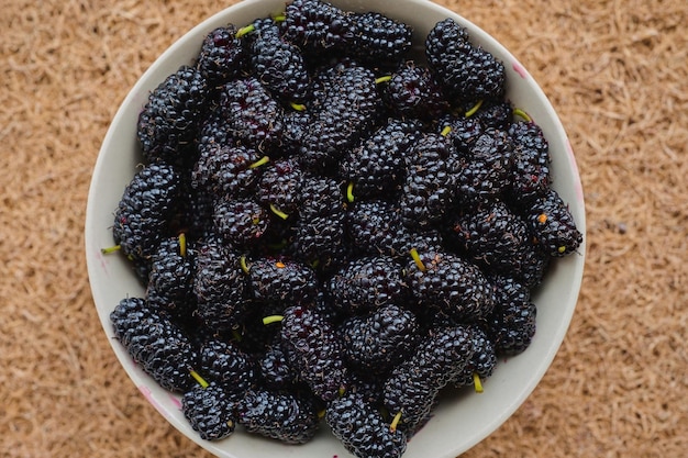 Reife Maulbeerbeeren in einer saisonalen Sommerbeere einer Keramikplatte von oben