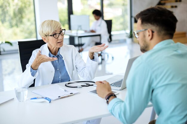 Reife Mitarbeiterin des Gesundheitswesens, die während eines Arzttermins in der Klinik mit ihrer Patientin spricht