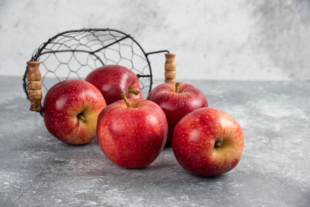 Kostenloses Foto reife organische rote äpfel aus metallkorb auf marmortisch.