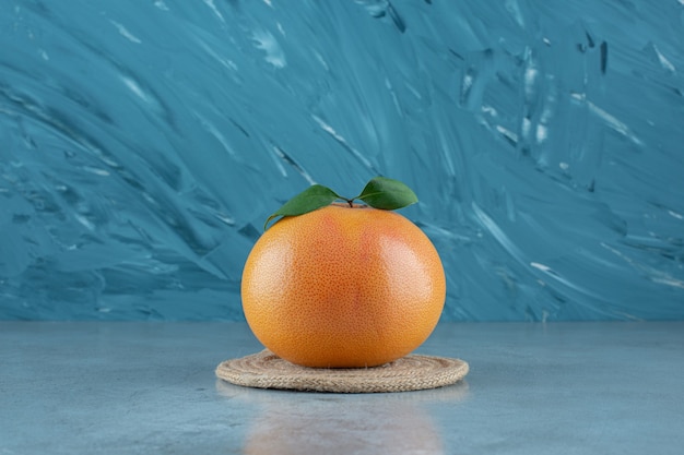 Reife saftige Orange auf einem Untersetzer, auf dem Marmorhintergrund.