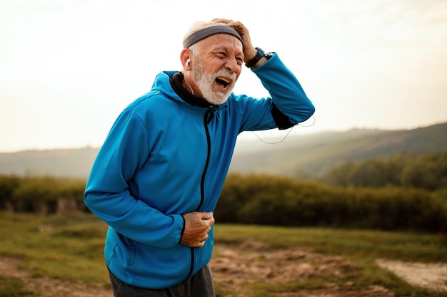 Reifer athletischer Mann, der beim Joggen in der Natur unter Kopfschmerzen leidet