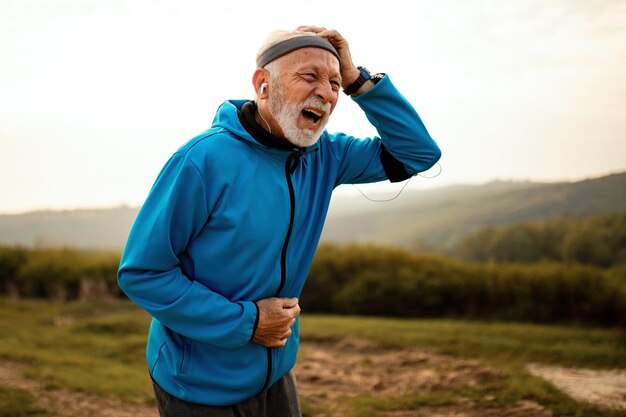 Reifer athletischer Mann, der beim Joggen in der Natur unter Kopfschmerzen leidet