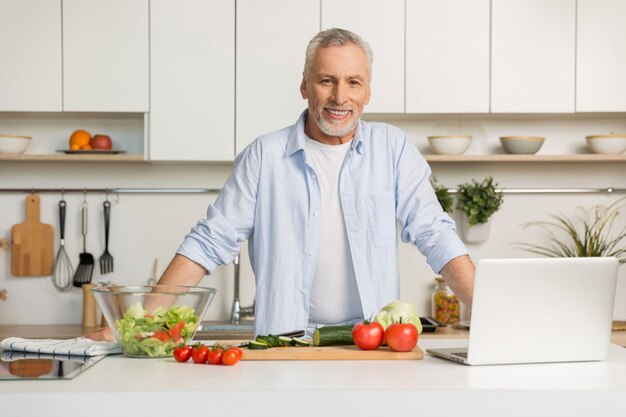 Reifer attraktiver Mann, der an der Küche kochend kocht