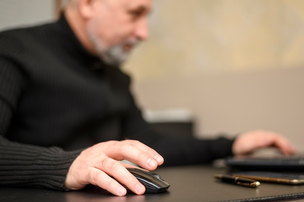 Reifer Mann, der an einem Laptop mit einer Maus arbeitet