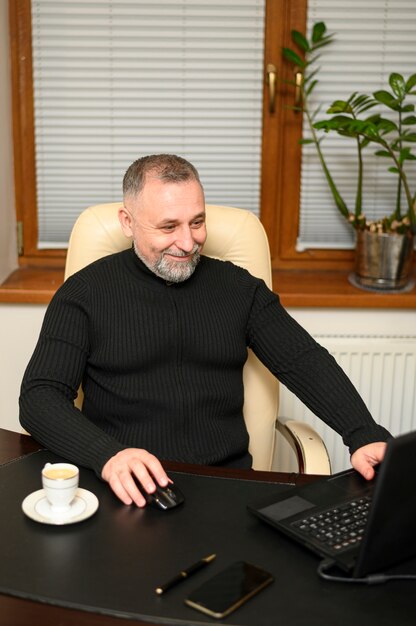 Kostenloses Foto reifer mann, der an seinem schreibtisch sitzt