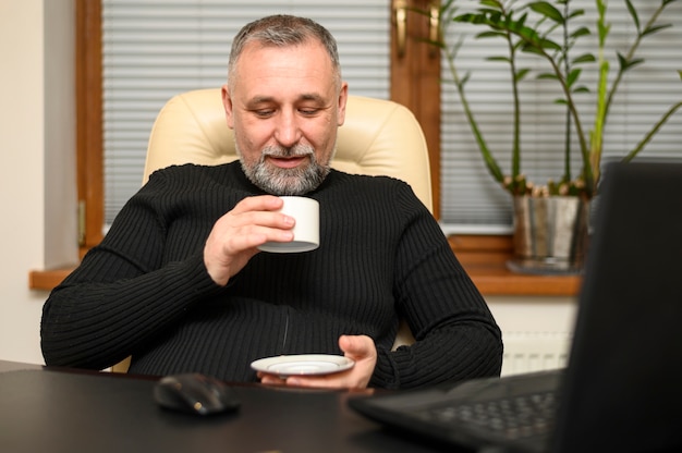 Kostenloses Foto reifer mann, der zu hause eine tasse kaffee hält