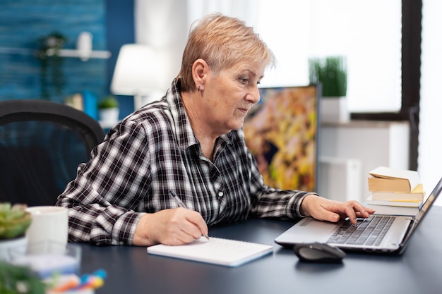 Reifer Unternehmer, der Notizen zum Notebook macht, das im Home Office arbeitet