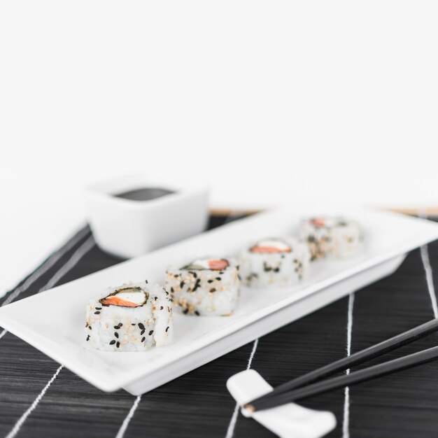 Reihe der Sushi auf weißem Behälter mit Essstäbchen