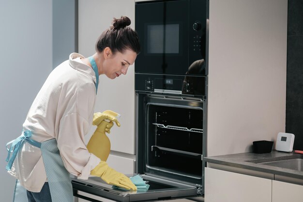 Reinigung der Küche. Hausfrau in gelben Handschuhen, die die Küche säubern