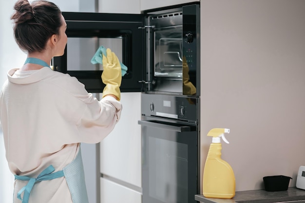 Reinigung der Küche. Hausfrau in gelben Handschuhen, die die Küche säubern
