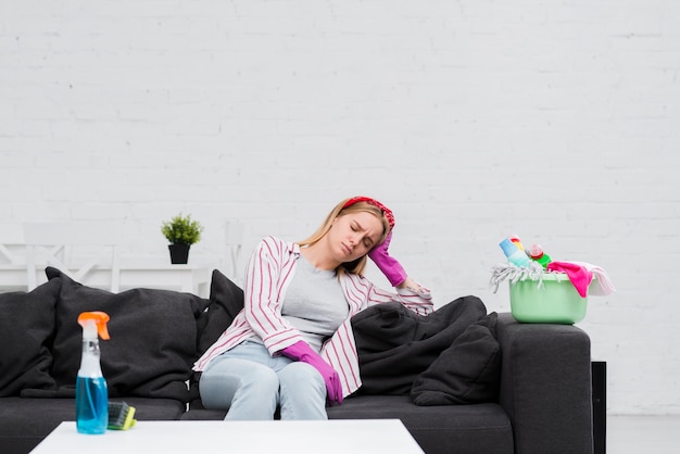 Reinigungsfrau in der Pause, die auf Couch sitzt