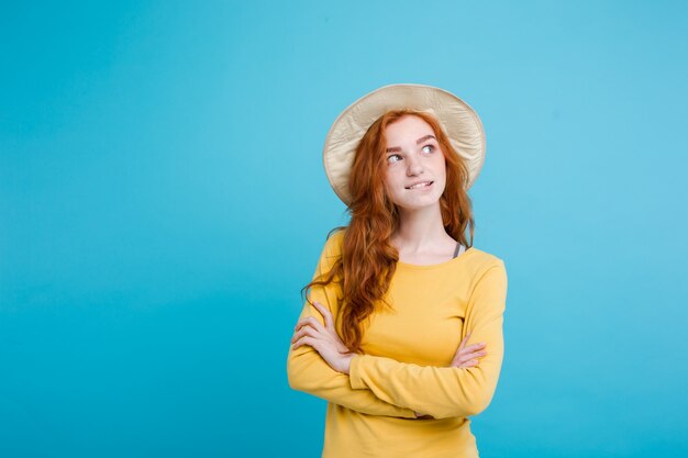 Reise-Konzept - Nahaufnahme Porträt junge schöne attraktive Redhair Mädchen mit trendy Hut und Sonnenbrille lächelnd. Blauer Pastellhintergrund. Platz kopieren