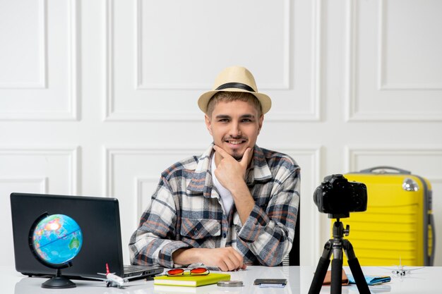 Reiseblogger, hübscher junger kerl, der reise-vlog vor der kamera mit gelbem gepäck aufzeichnet, aufgeregt