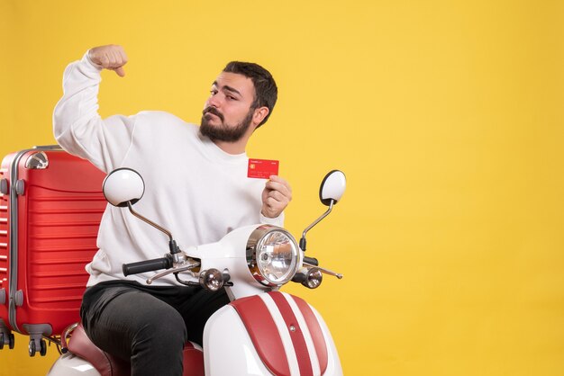 Reisekonzept mit dem jungen lächelnden glücklichen reisenden Mann, der auf dem Motorrad sitzt