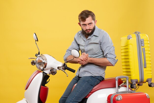 Reisekonzept mit jungem enttäuschtem bärtigem Mann, der auf Motorrad auf auf Gelb sitzt
