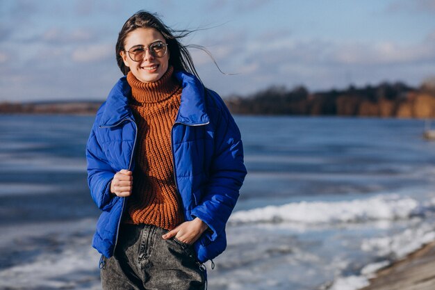 Reisende der jungen Frau in der blauen Jacke auf dem Strand