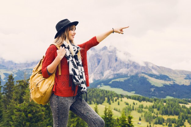 Reisende Frau mit Hut und Rucksack, die erstaunlichen Bergblick genießen