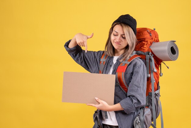 Reisende Frau mit Rucksack auf Karton zeigend