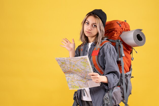 Reisende Frau mit Rucksack hält Karte auf Gelb
