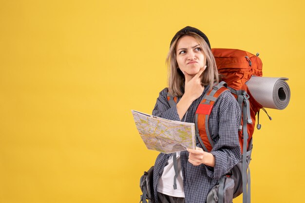 Reisende Frau mit Rucksack mit Karte, die über die Reise nachdenkt