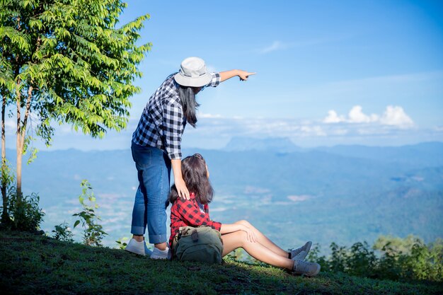 Reisende, junge Frauen, schauen sich die erstaunlichen Berge und Wälder an, lassen sich von Reiselust inspirieren,