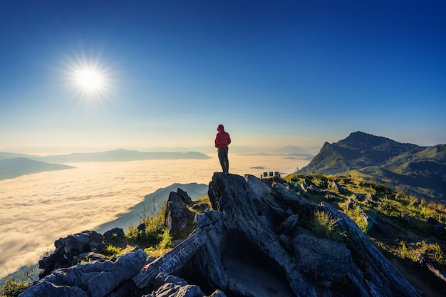 Reisender, der auf dem Felsen, Doi Pha Tang und Morgennebel in Chiang Rai, Thailand steht.