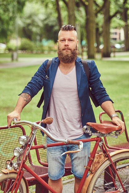 Reisender mit einem Rucksack, der sich in einem Stadtpark entspannt, nachdem er auf einem Retro-Fahrrad gefahren ist.