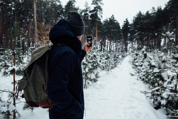 Reisender nimmt Selfie der schneebedeckten Landschaft im Winterwald am Handy