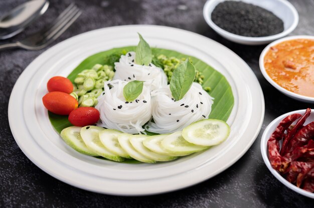 Reisnudeln in einem Bananenblatt mit schön gelegtem Gemüse und Beilagen. Thai Essen.