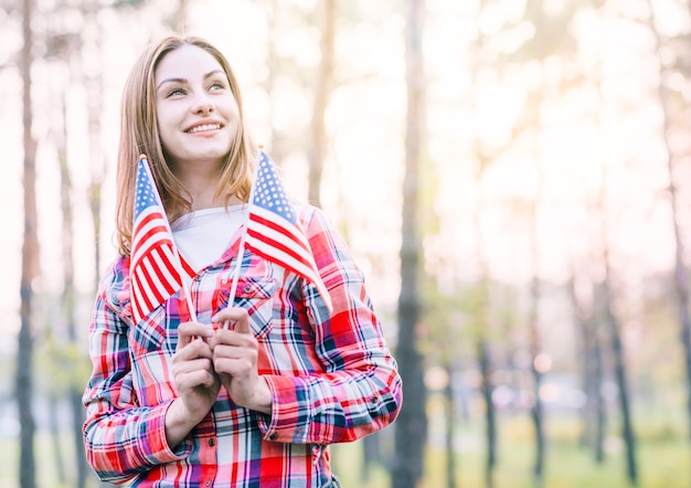 Reizend junge Frau, die kleine amerikanische Flaggen hält