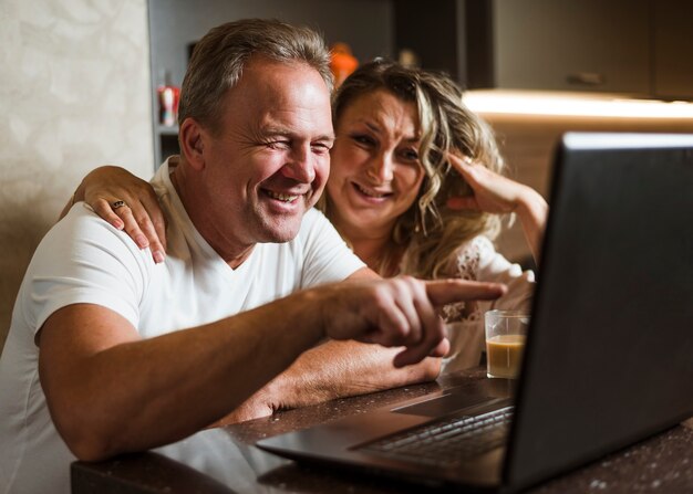 Reizende ältere Paare, die am Laptop lachen